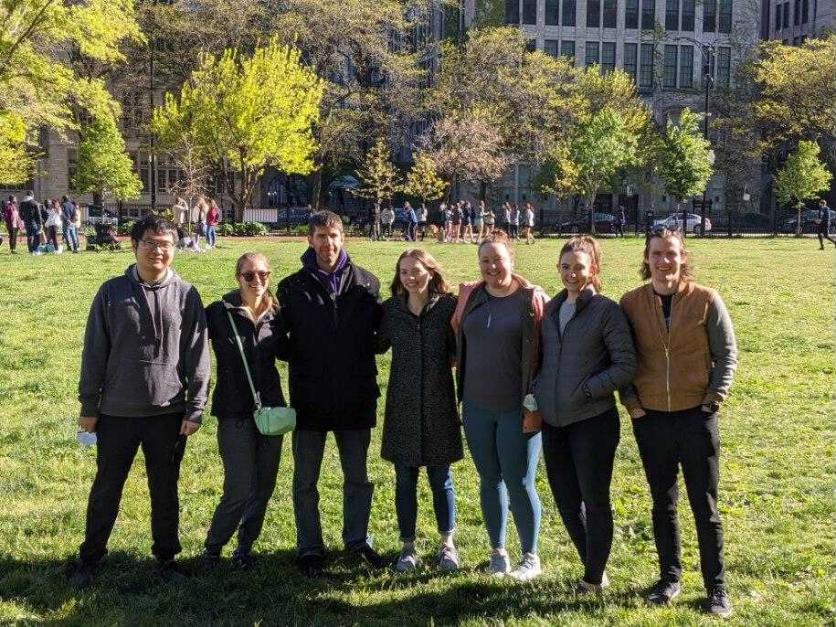 Members posing and smiling by a grassy area in Chicago