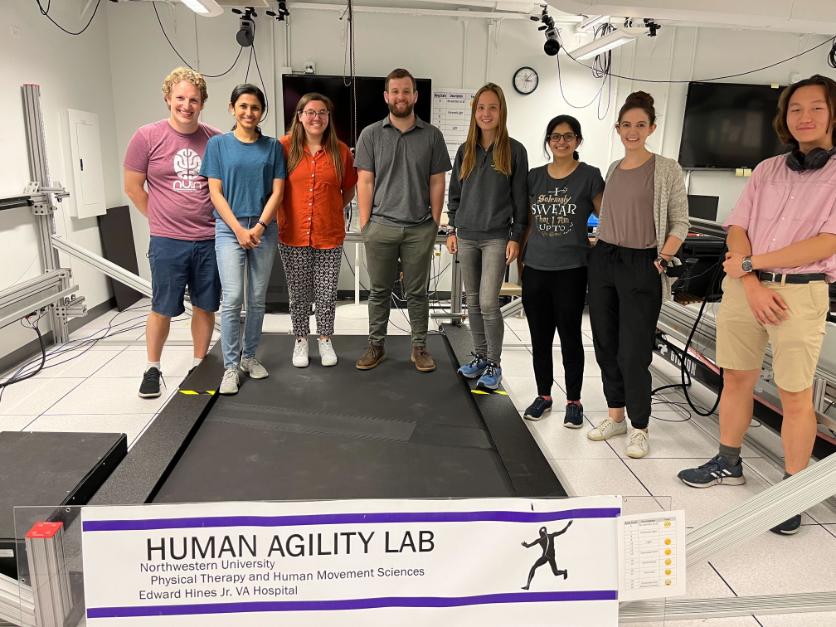 Members standing and smiling with a "Human Agility Lab" sign