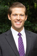 Portrait of Andrew Christopherson in a suit smiling.