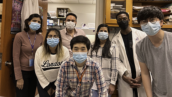 A group of masked lab members pose in the lab